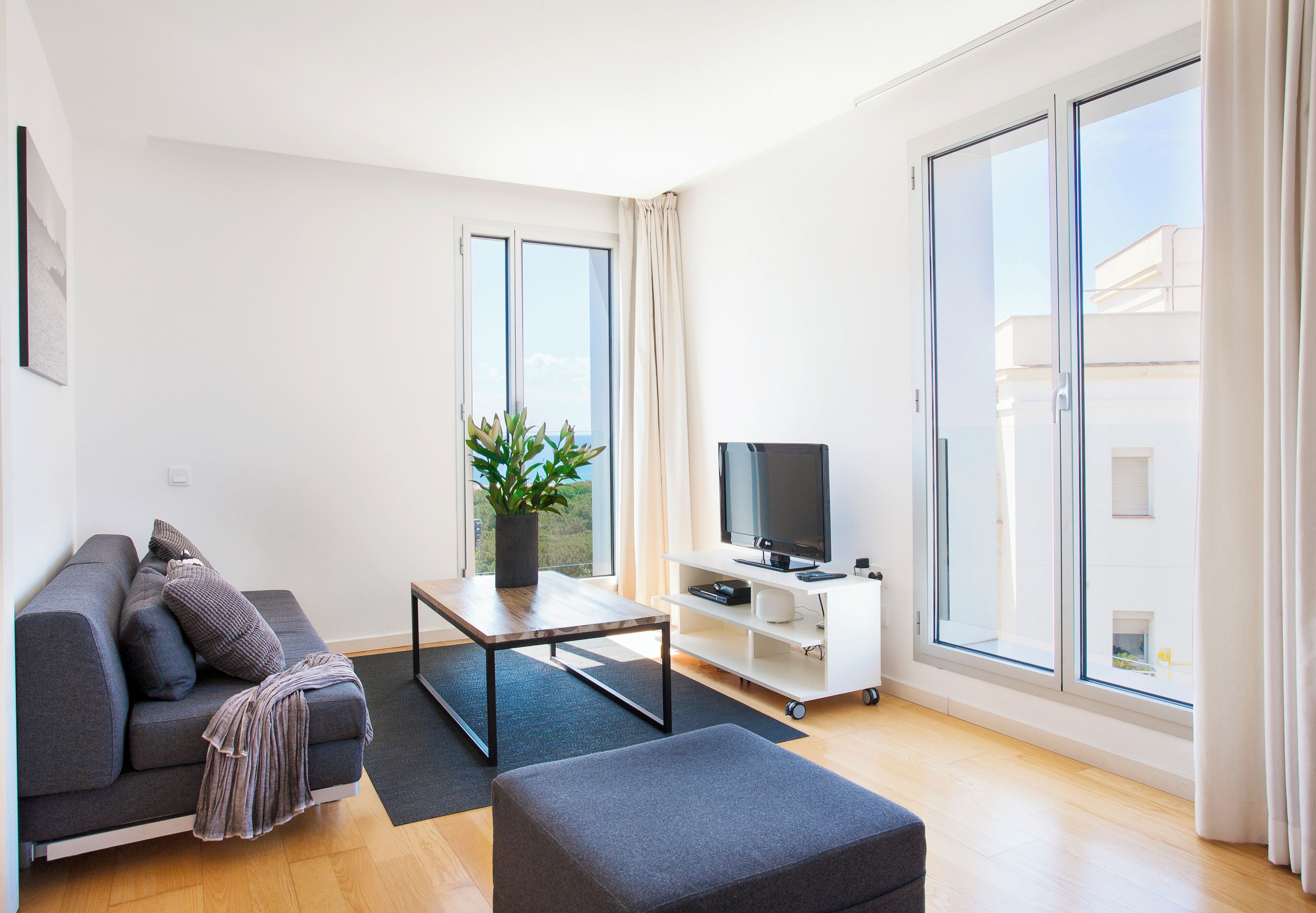 Una sala de estar moderna con un sofá, una mesa de centro, un televisor y un gran ventanal corredizo.