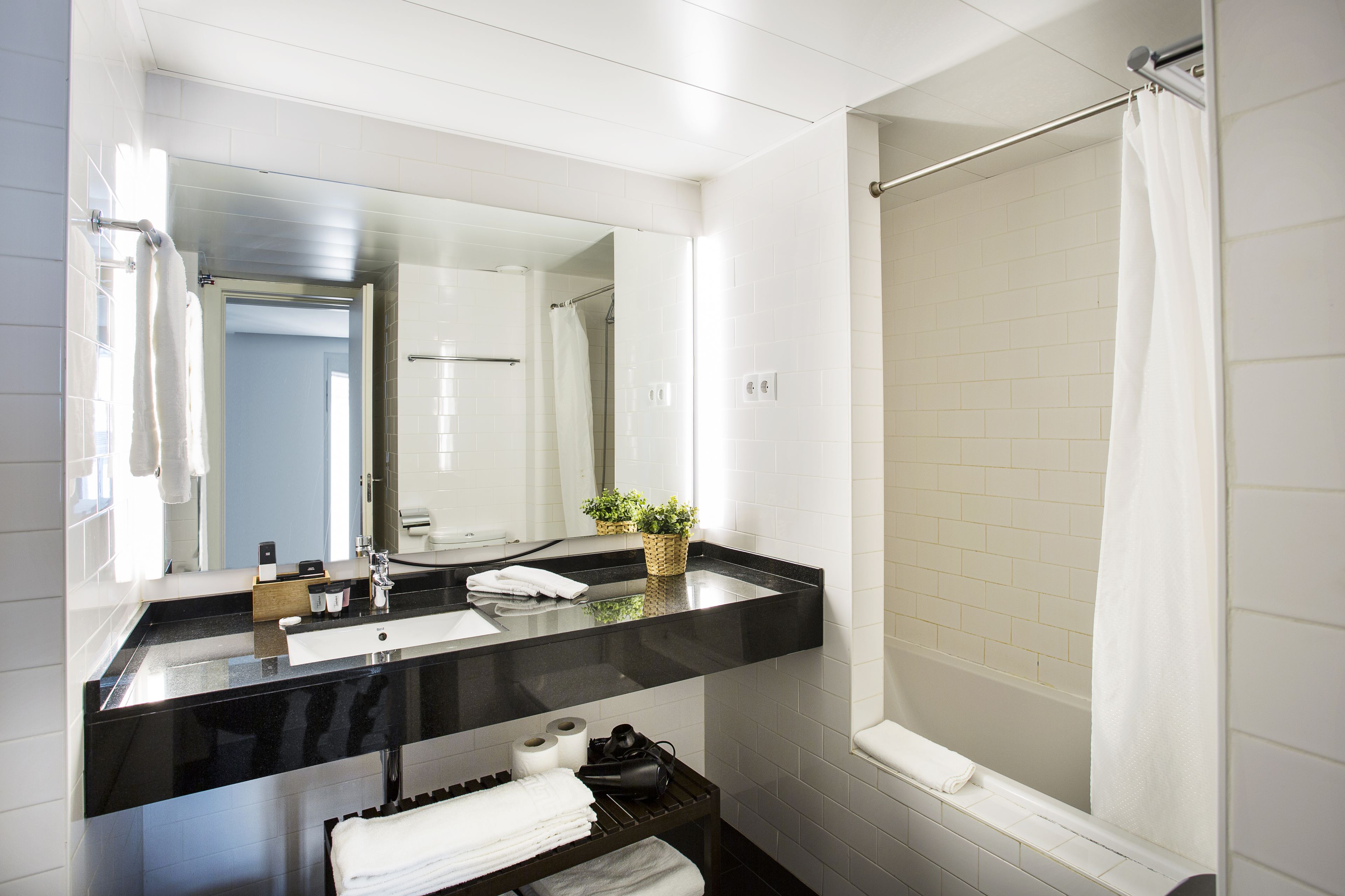 Un baño moderno con encimera negra, lavabo blanco y un espejo grande.