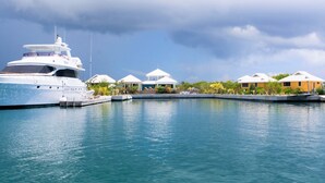 A yacht docked at a marina with several beachside villas. - Barefoot Cay Resort (Roatan)