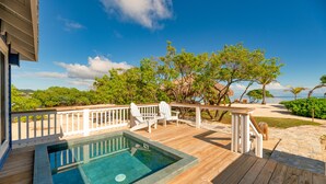A wooden deck with a swimming pool, white deck chairs, and a view of the beach and ocean. - Barefoot Cay Resort (Roatan)