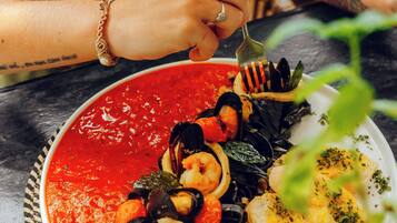 A plate of seafood pasta with a red sauce, served on a woven placemat.