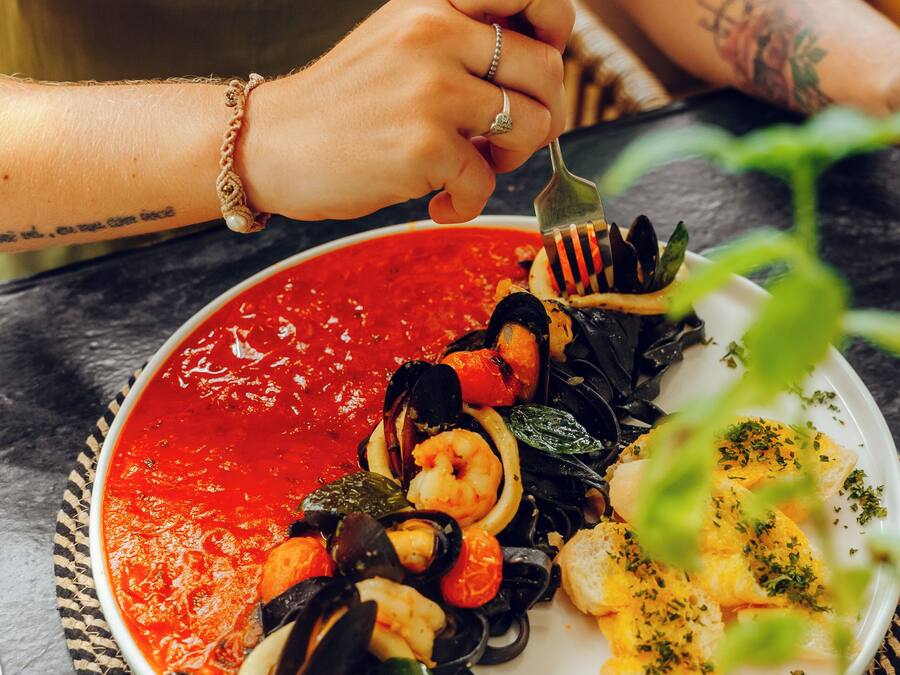 A plate of seafood pasta with a red sauce, served on a woven placemat.