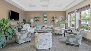 A spacious lobby with a sofa, armchairs, a coffee table, and potted plants.