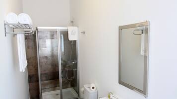 A modern bathroom with a glass shower enclosure, a white toilet, and a sink with blue cups.