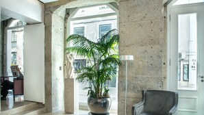 Eine Lobby mit einer großen Topfpflanze, einem modernen Sessel und Blick auf die Straße durch einen Bogen.