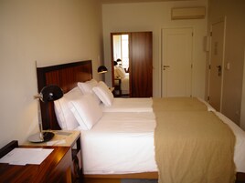 Une chambre d’hôtel avec deux lits, un bureau avec des papiers, une lampe et une armoire.