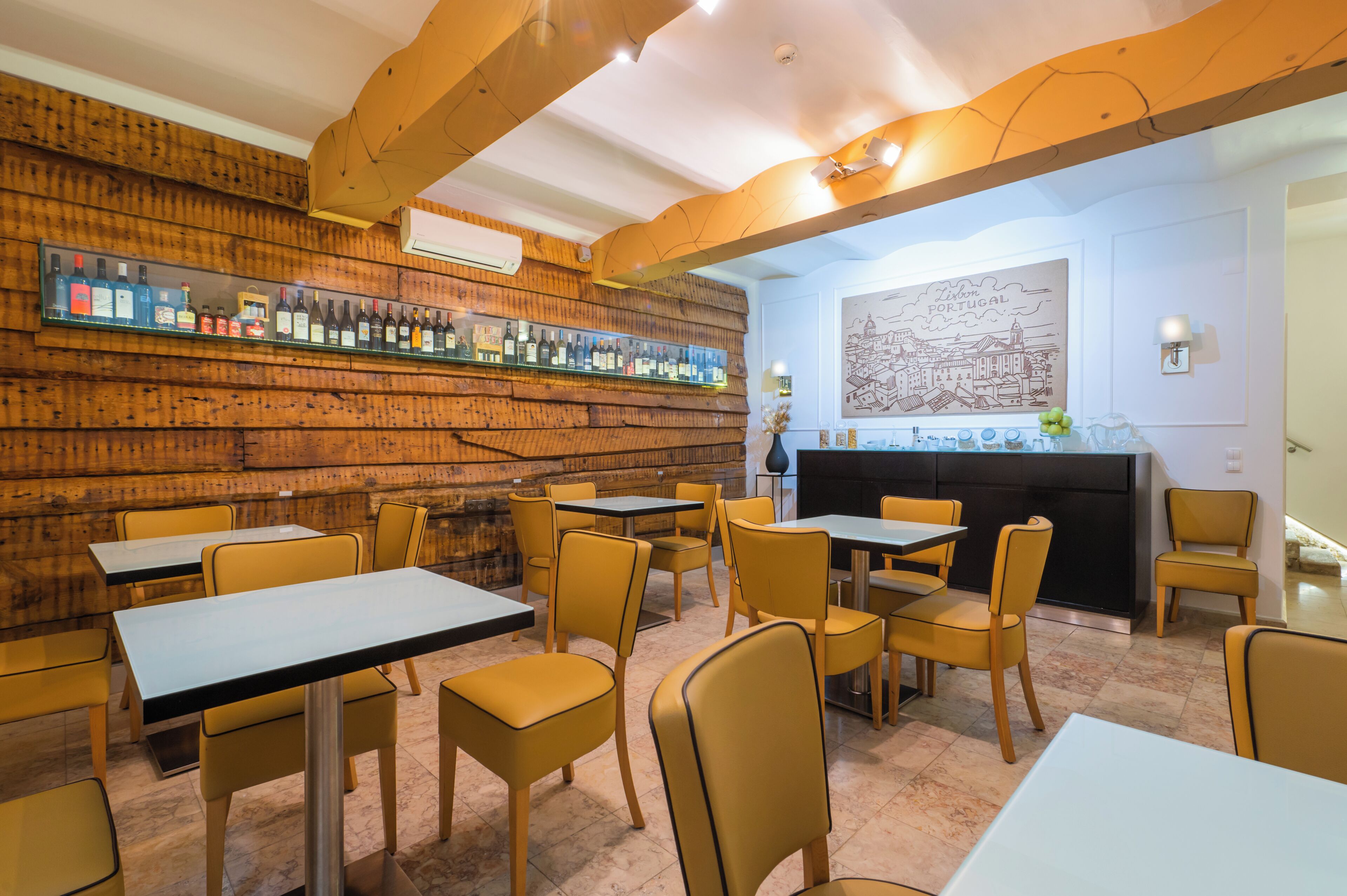 Interior de restaurante con paredes de madera, zona de bar y mesas con sillas.