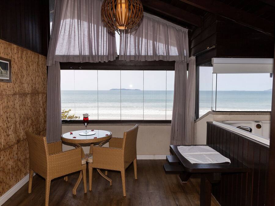 Une chambre avec vue sur l’océan, une table avec des chaises, un petit lit et un mur en bois.