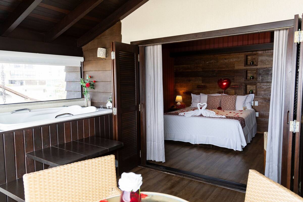 Habitación de hotel con cama, baño con bañera y vistas de la ciudad.