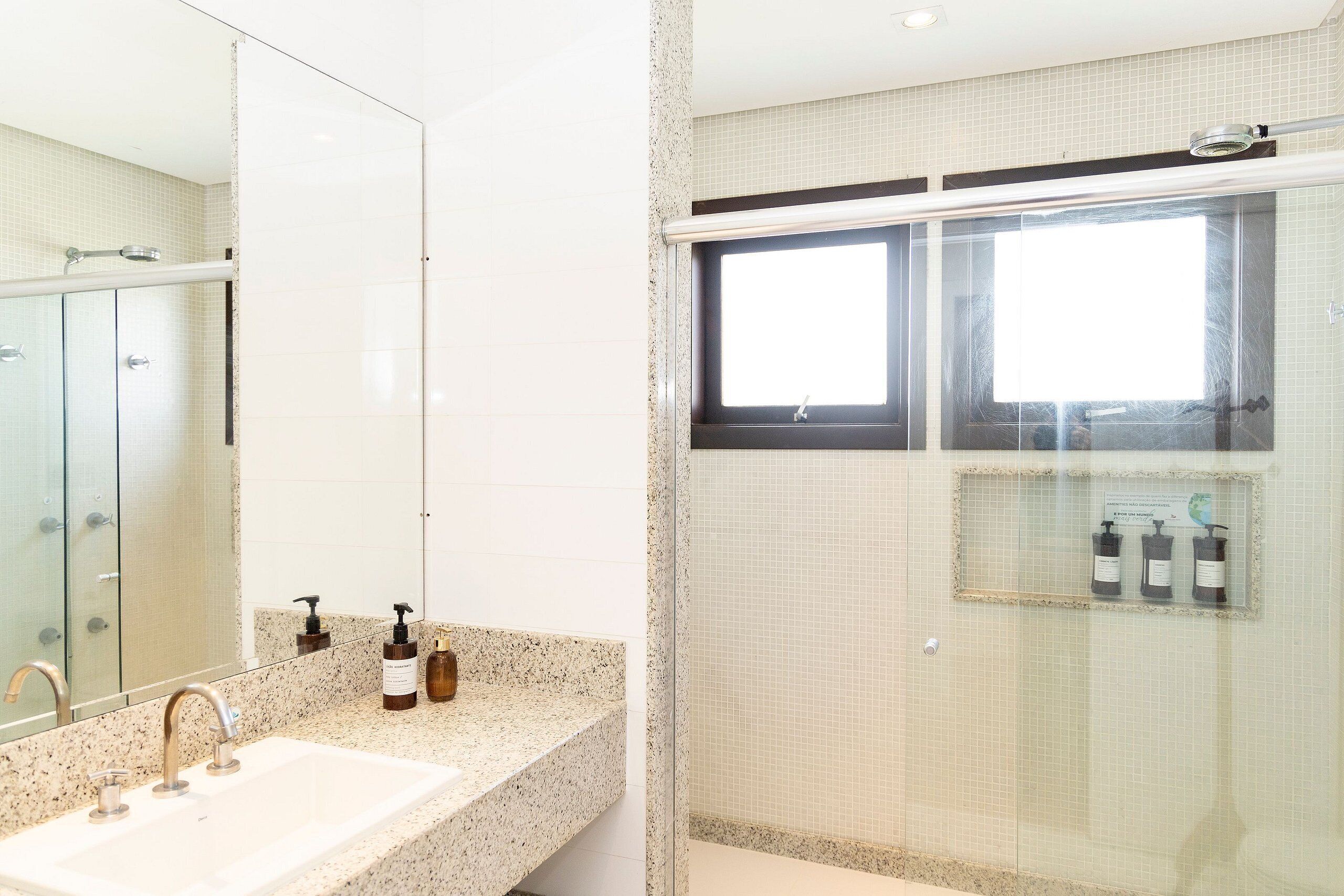 Ein Badezimmer mit Waschbecken, Spiegel, Dusche und Toilettenartikeln.