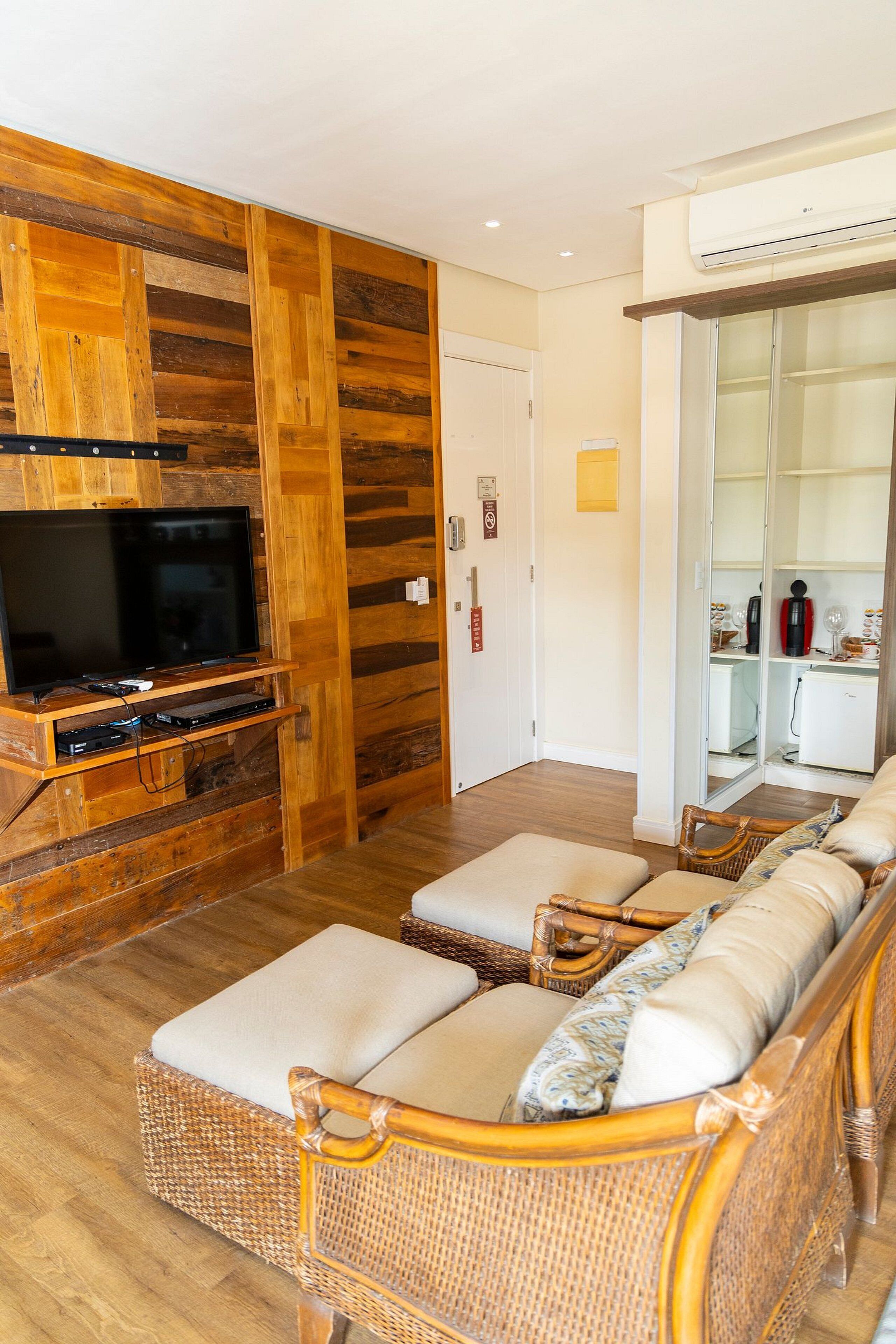 A living room with a television, wicker sofa, and wooden panel walls.