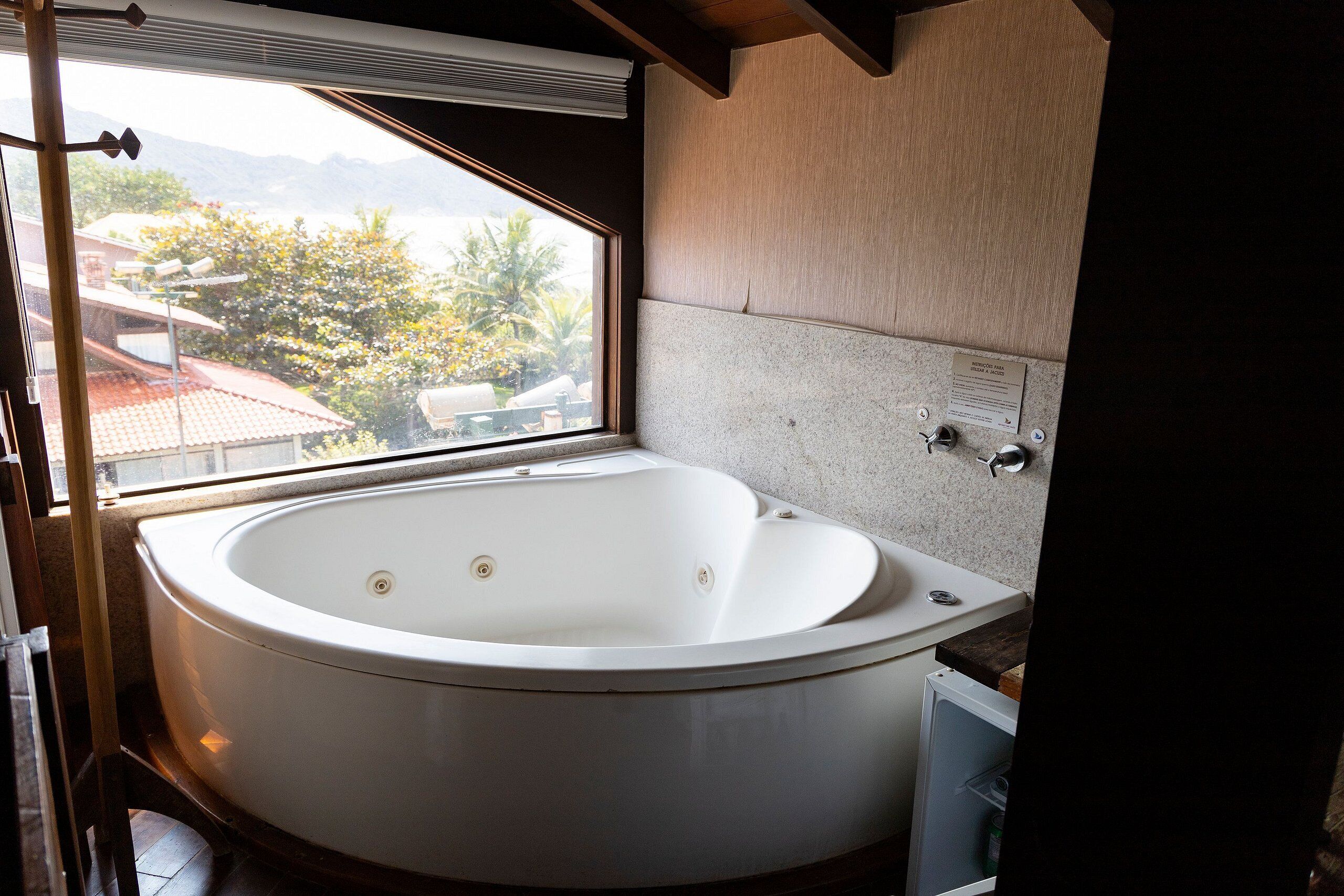 A large, round bathtub in a bathroom with a view of a residential area.