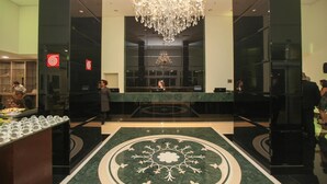 En reception med central skranke, en lysekrone og et mønstret gulv.