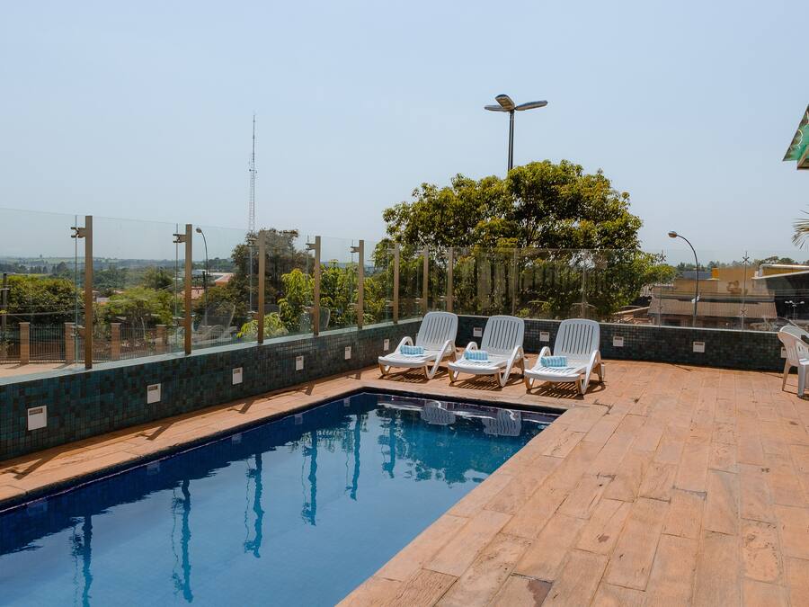 Piscina en la azotea con sillones de descanso y vistas a la ciudad.