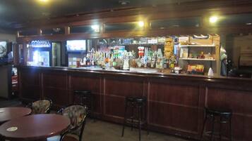 A bar area with a counter, stools, and tables.