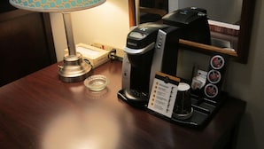 Una cafetera, una lámpara y un atril para menús sobre una mesa de madera.