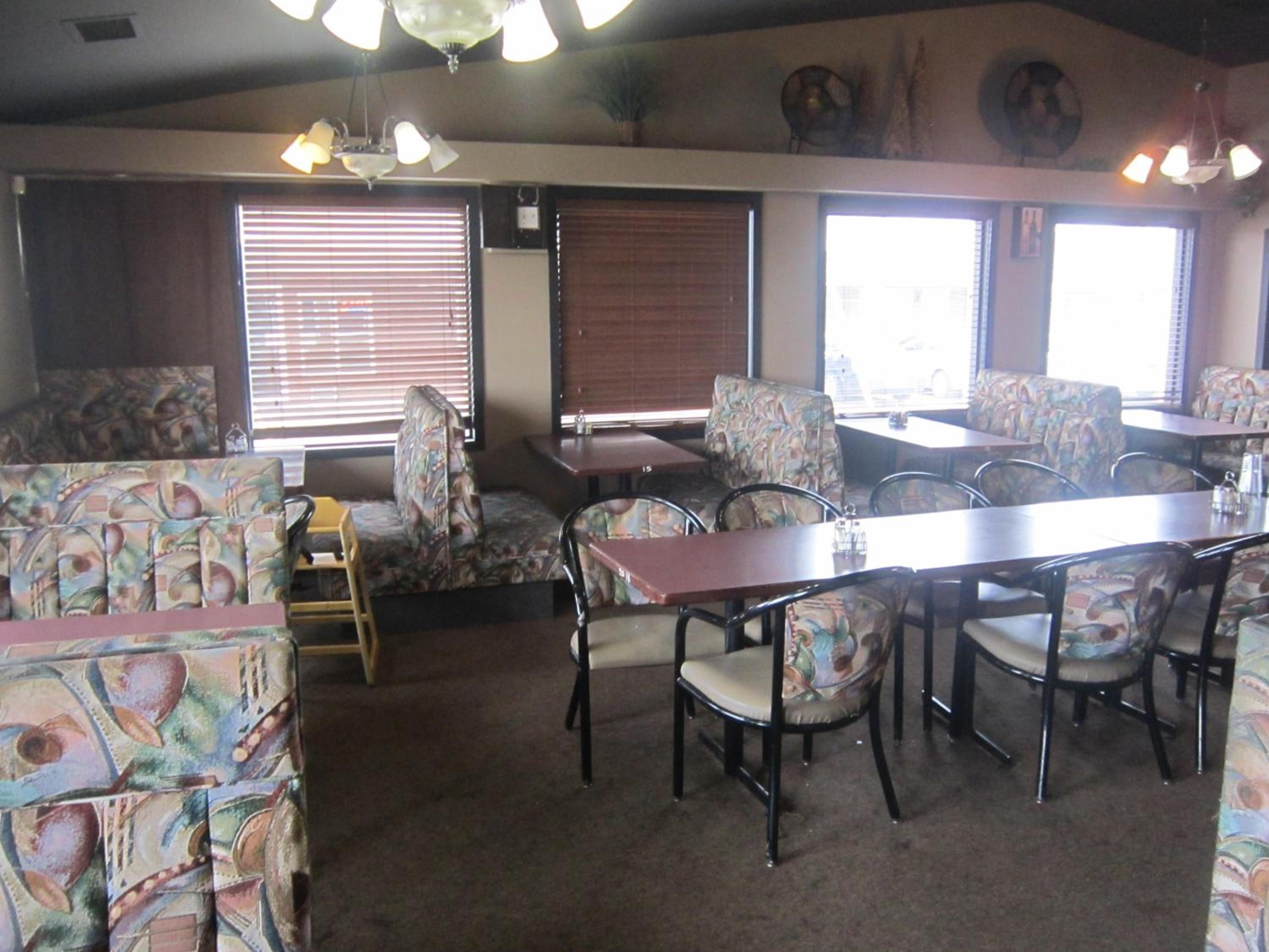 Un espace repas avec des banquettes et des tables, des revêtements d’assise à motifs et un ventilateur de plafond.