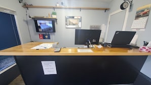 Mostrador de recepción con computadora, teléfono y señal que indica horario de silencio después de las 23:00.