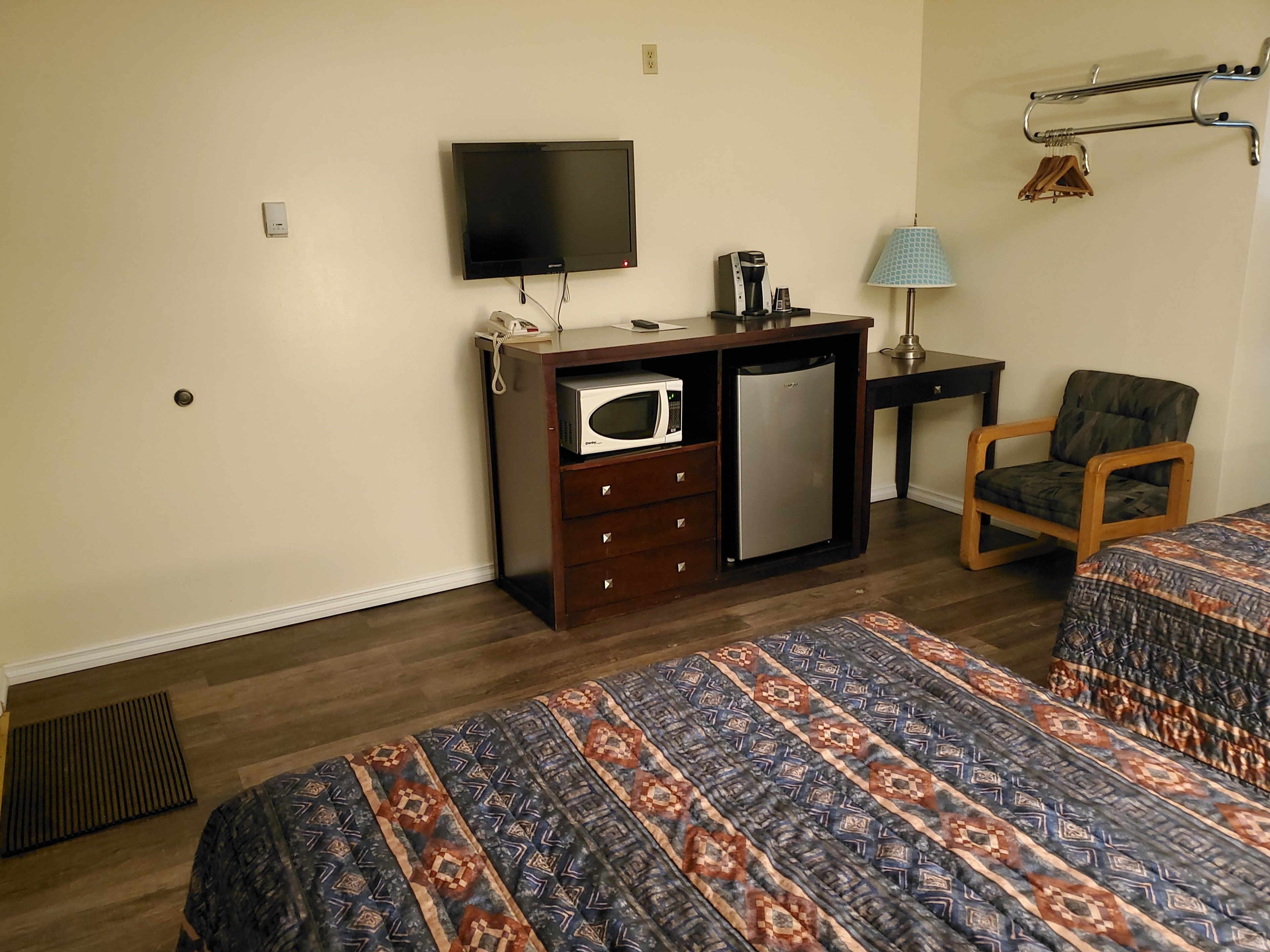 Une chambre d’hôtel équipée d’un lit, d’un bureau avec un micro-ondes, d’un réfrigérateur, d’une télévision et d’une chaise.