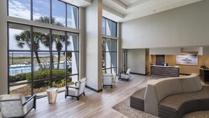 A spacious lobby with large windows, a reception desk, and a pool view. - Island House Hotel Orange Beach - a DoubleTree by Hilton (Orange Beach)