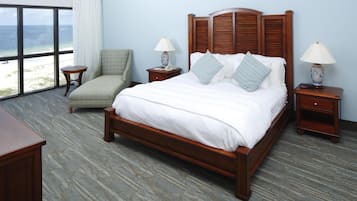 A hotel room with a large bed, two bedside tables with lamps, a chair, and a view of the ocean.