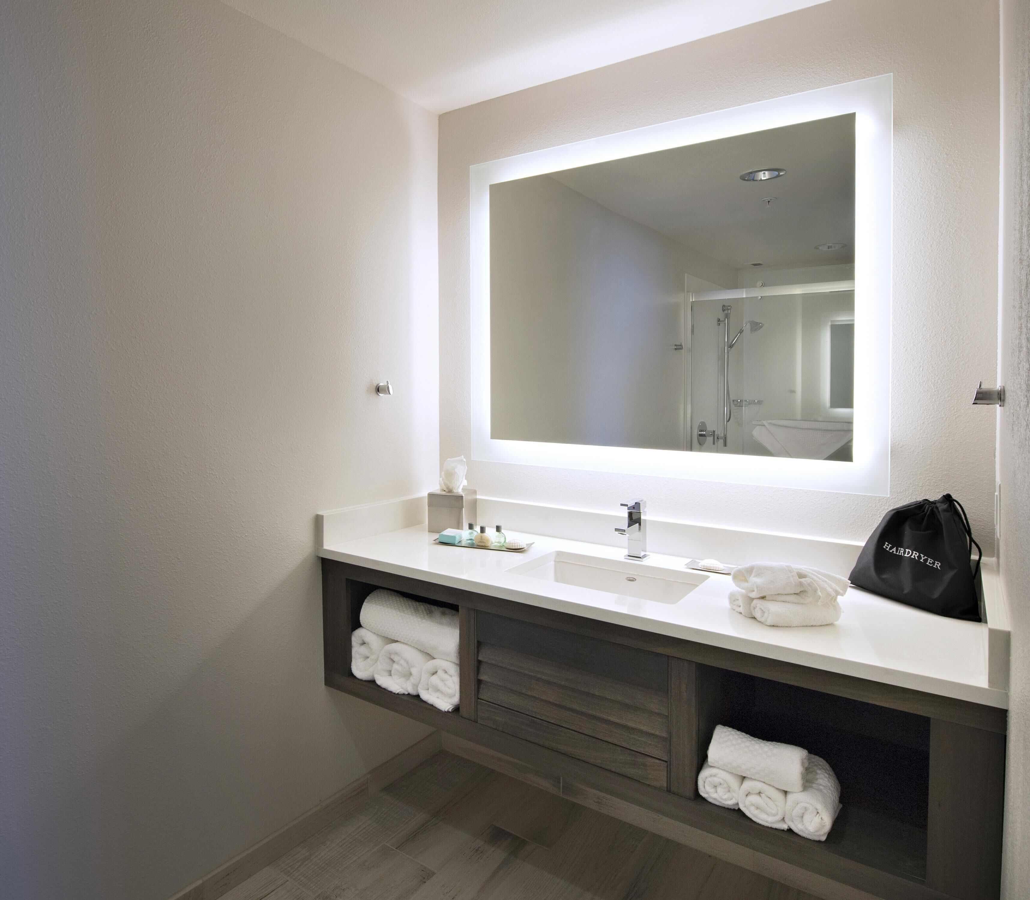 A modern bathroom with a large mirror, dual sinks, and a towel rack.
