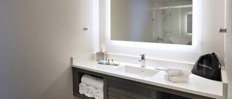 A modern bathroom with a large mirror, dual sinks, and a towel rack.