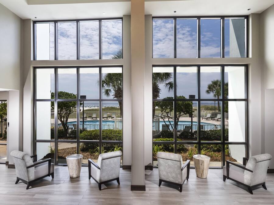 A spacious room with large windows, a pool view, and modern furniture.