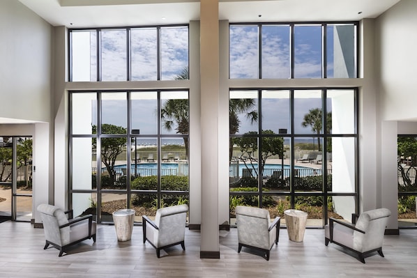 A spacious room with large windows, a pool view, and modern furniture.