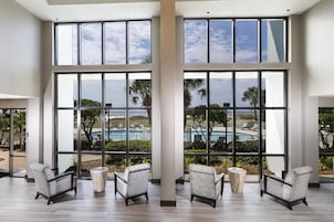 A spacious room with large windows, a pool view, and modern furniture.