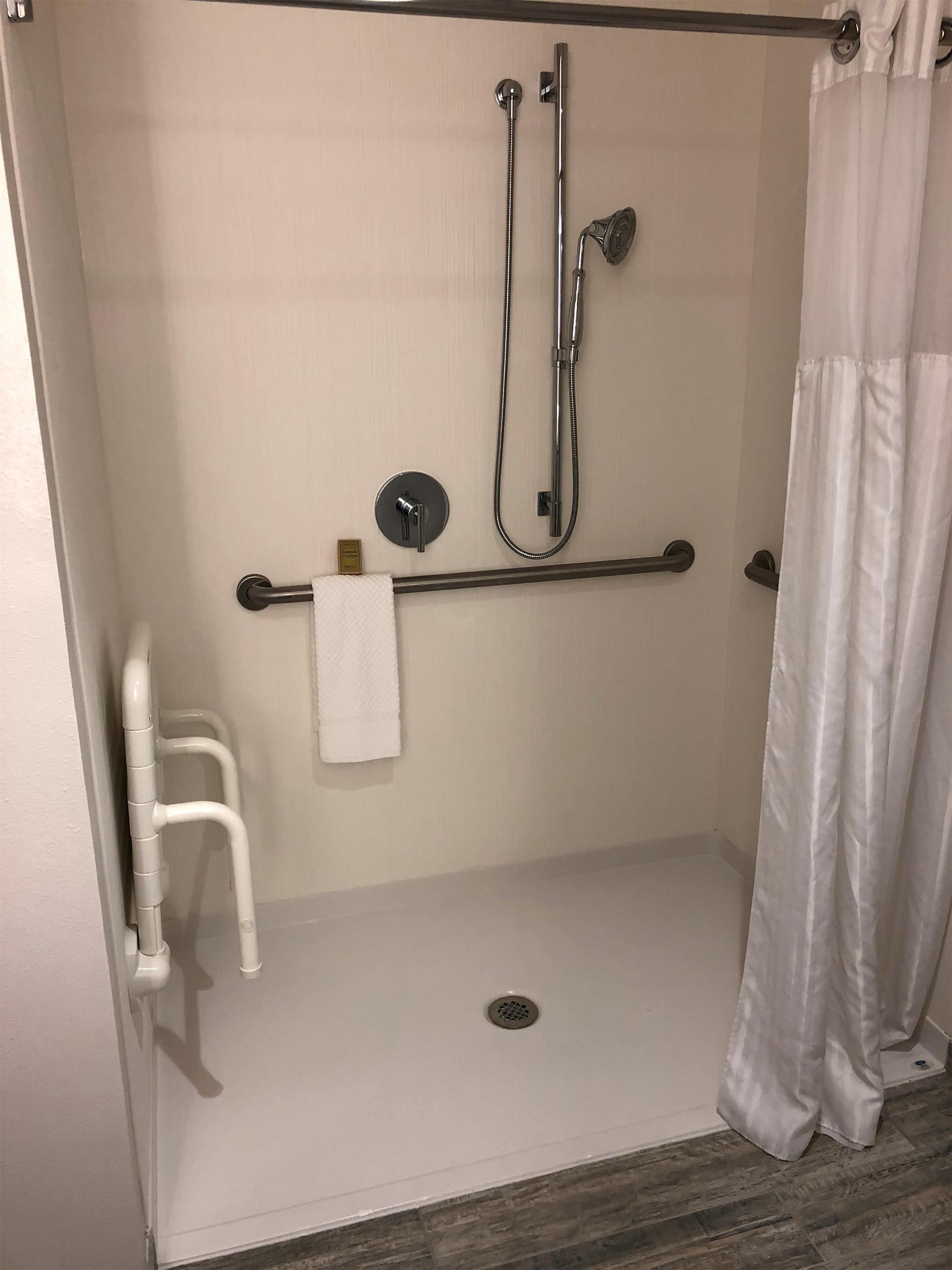 A walk-in shower with a grab bar, a towel rack, and a showerhead.