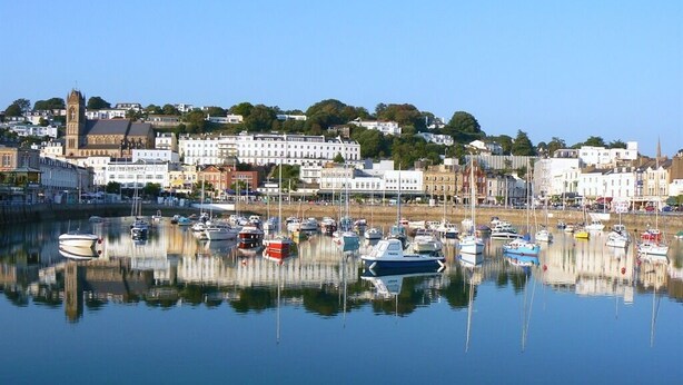 A harbor with numerous boats docked, a prominent church, and a mix of residential and commercial buildings. - Ashleigh House (Torquay)