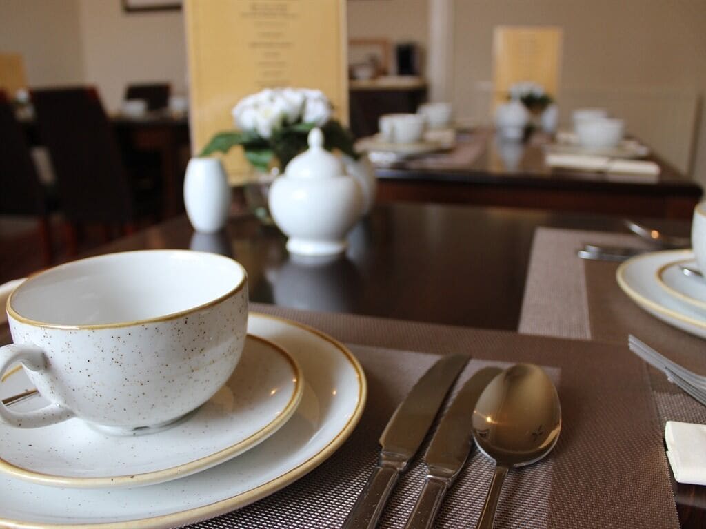 Una mesa de comedor dispuesta con taza, platillo, cuchillo y cuchara.