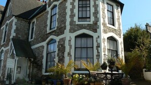 A large, two-story stone house with multiple windows and a prominent front porch. - Ashleigh House (Torquay)