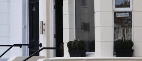A building with a staircase leading to a door marked "Sen." and a sign above the door that reads "NO VACANCY."