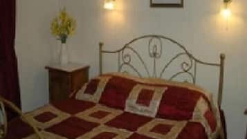 A bed with a metal frame and a red and beige quilt. There are two wall sconces on either side of the bed.