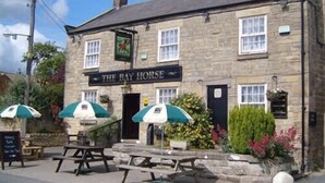 A stone building with a sign reading "The Bay Horse" and outdoor seating with umbrellas. - The Bay Horse Country Inn (Thirsk)