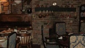 A rustic dining area with brick walls, wooden furniture, and a variety of decorative items including a clock and hanging pots. - The Bay Horse Country Inn (Thirsk)