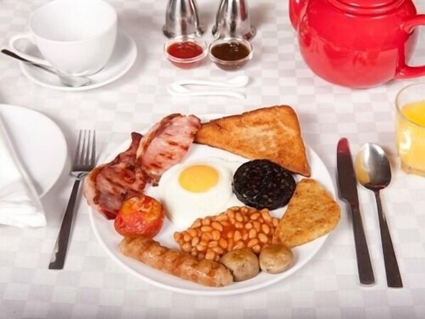 Un plato de desayuno con tostadas, tocino, huevos, frijoles, champiñones y salchichas.