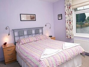 A bedroom with a bed, bedside tables, a window with curtains, and wall-mounted lights. - Holbrook B&B (Shaftesbury)