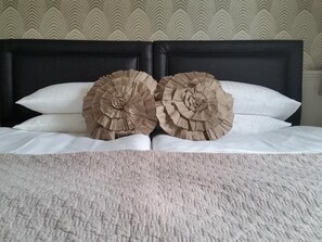 A bed with a textured white bedspread and two large, ruffled, beige decorative pillows. - Gallery Guesthouse (Plymouth)