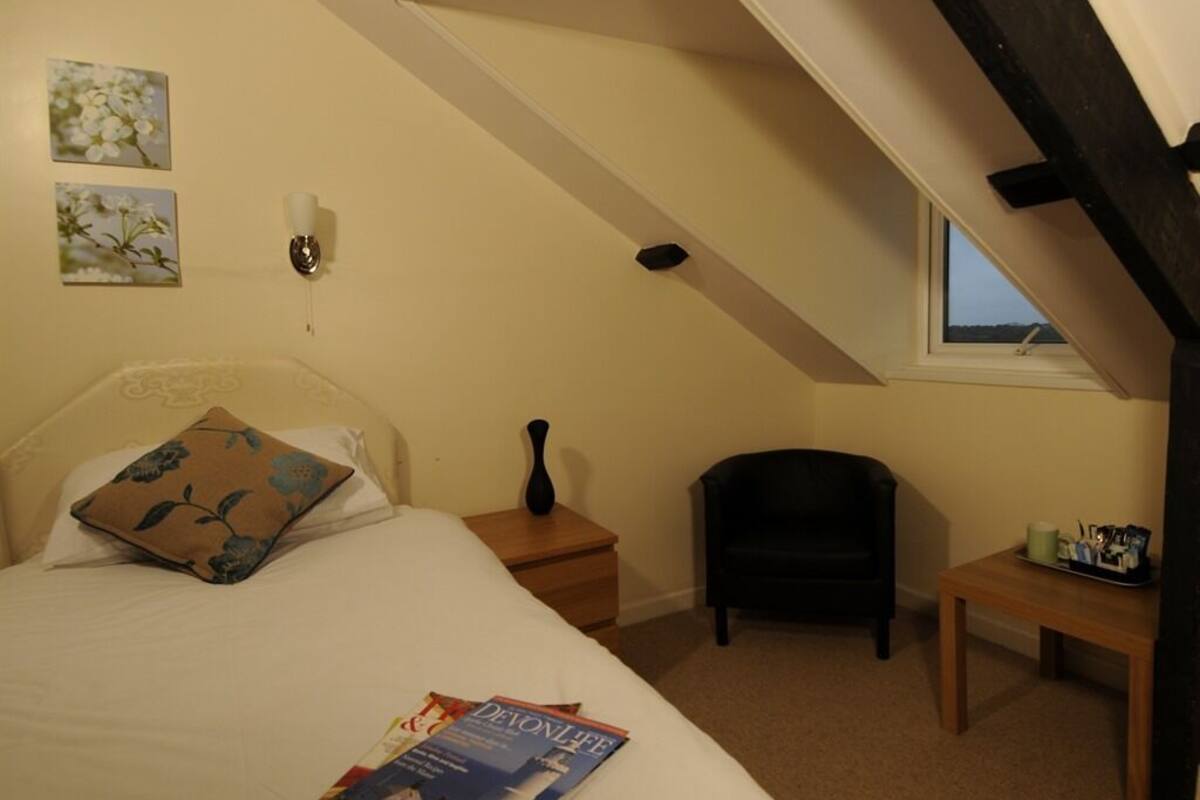 A bedroom with a bed, a nightstand, a chair, a small table, and a window.