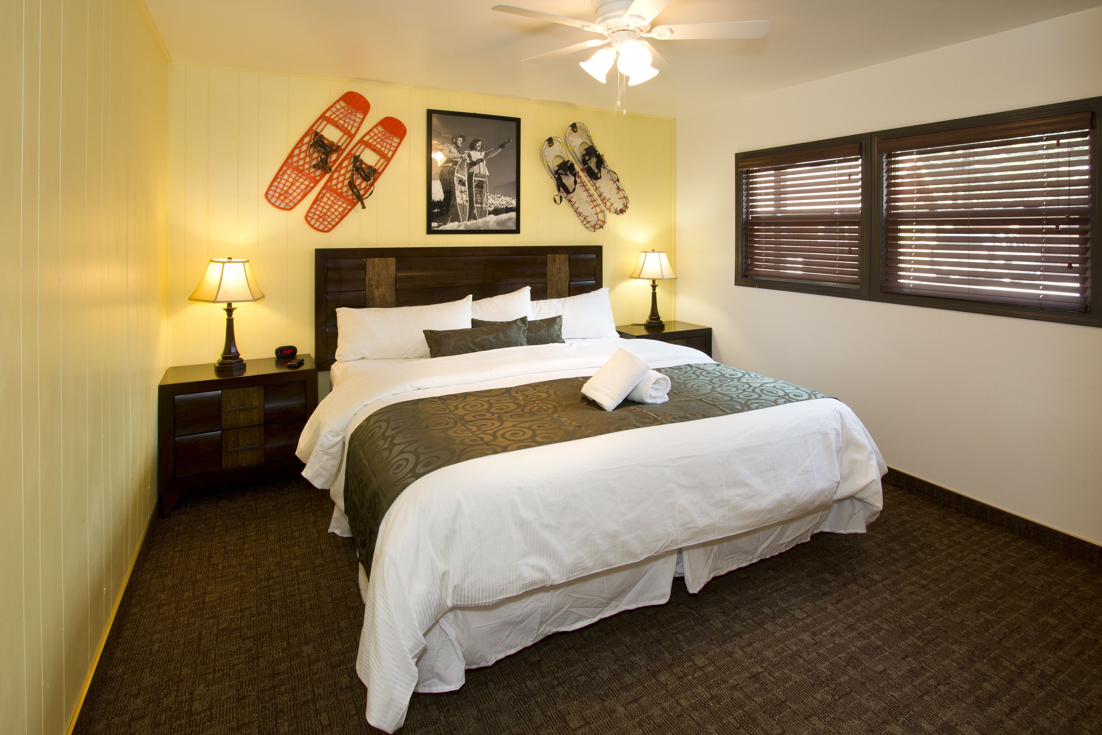 A neatly made bed with white linens, two bedside lamps, and a headboard.