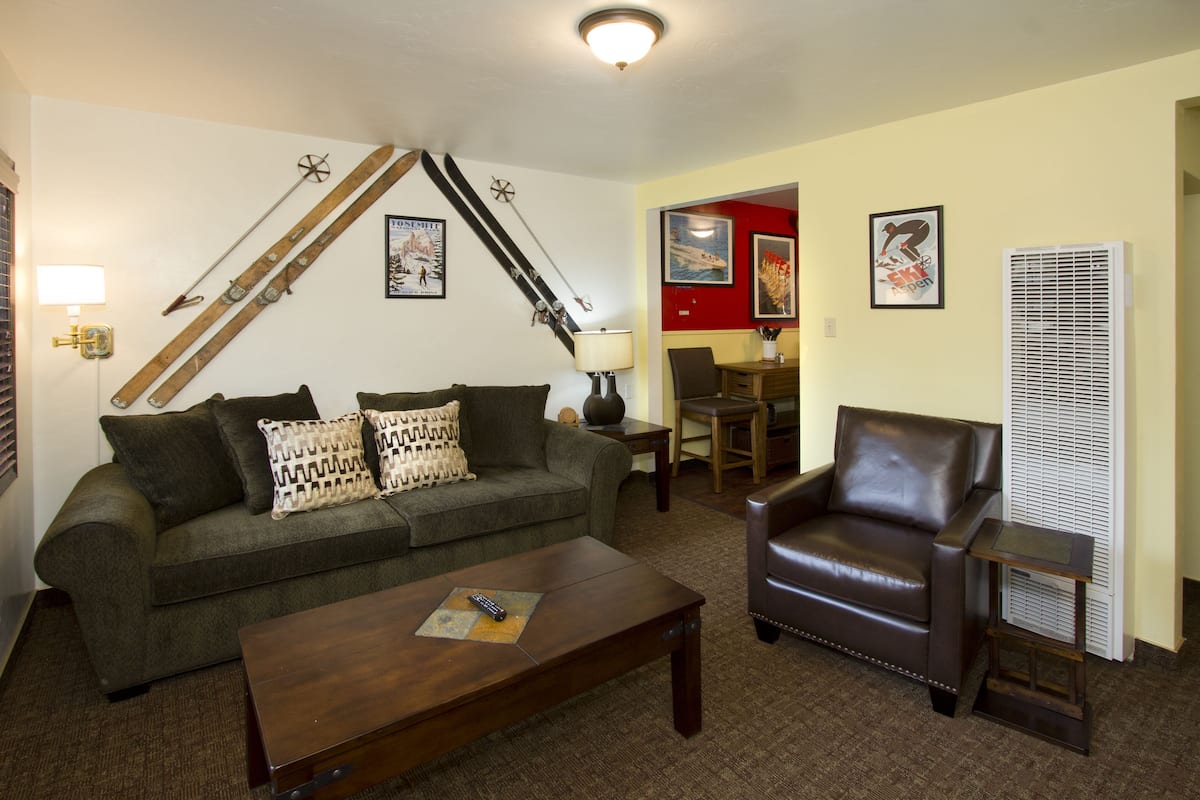 A living room with a sofa, a coffee table, a leather armchair, and a fireplace.