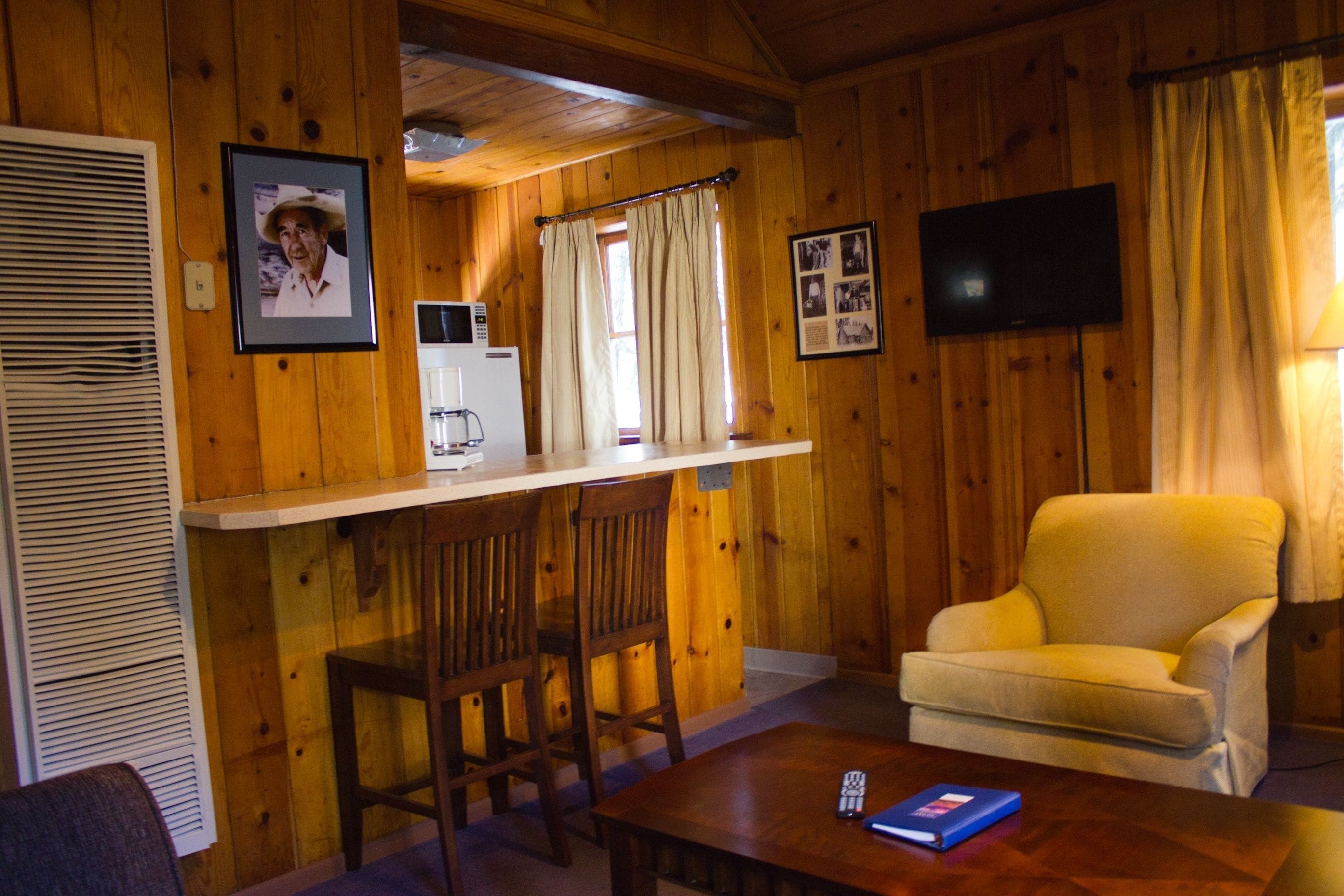 L’intérieur d’une cabane en bois comprend un coin cuisine, un téléviseur, un canapé et un espace repas.