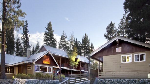 A lodge with a wooden exterior, a balcony, and a stone wall. - Holiday Haus Motel (Mammoth Lakes)