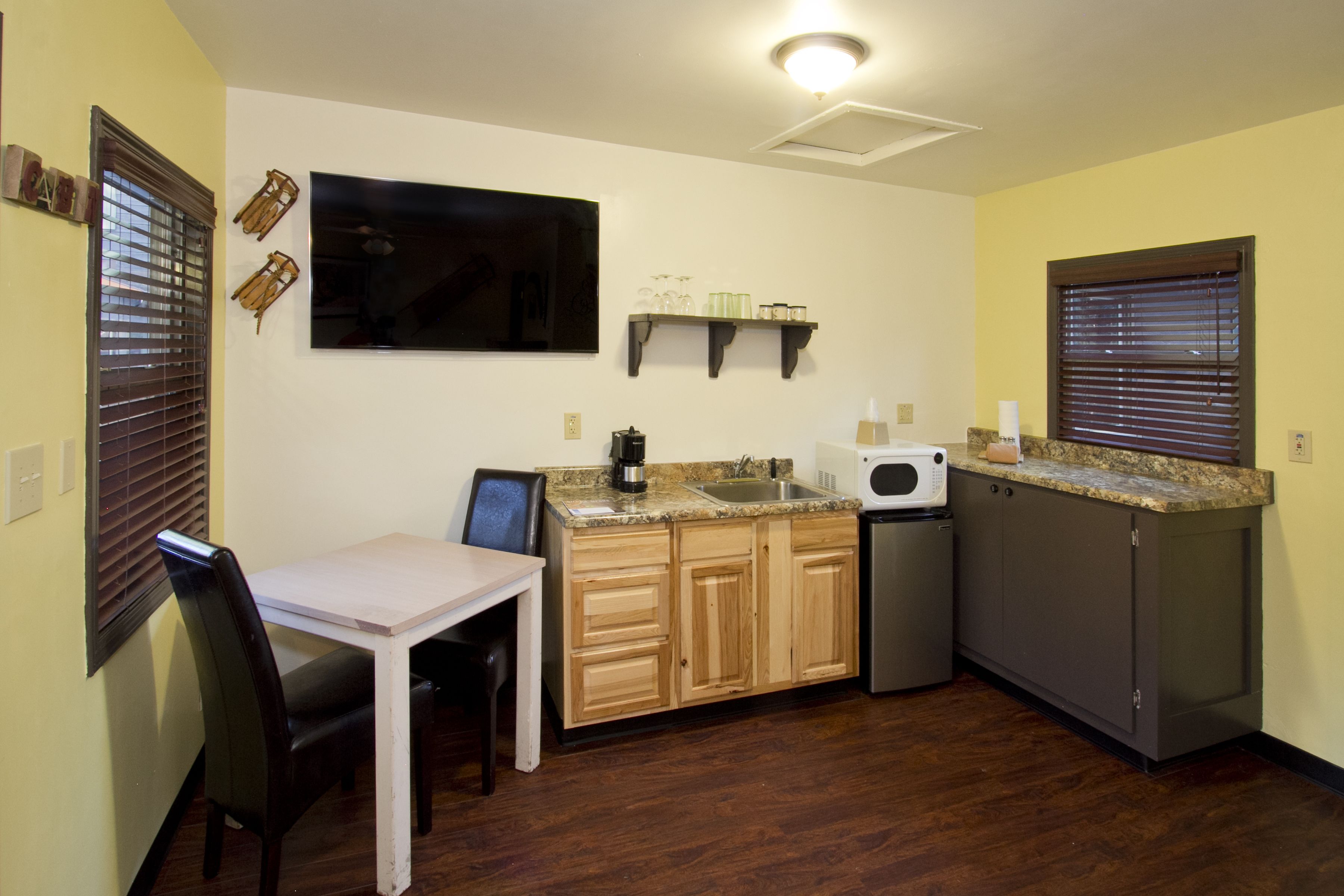 A compact kitchen with wooden cabinets, a granite countertop, a microwave, and a small sink.