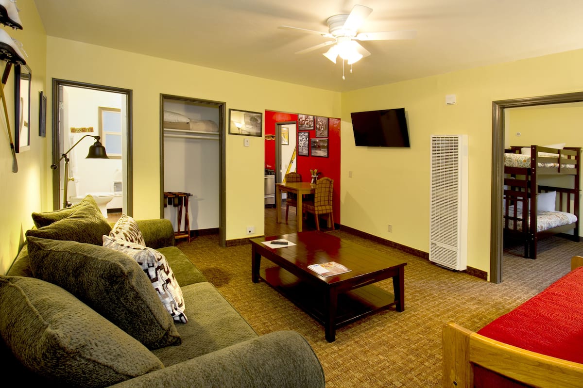 A compact living space with a sofa, a coffee table, a television, and a bunk bed.