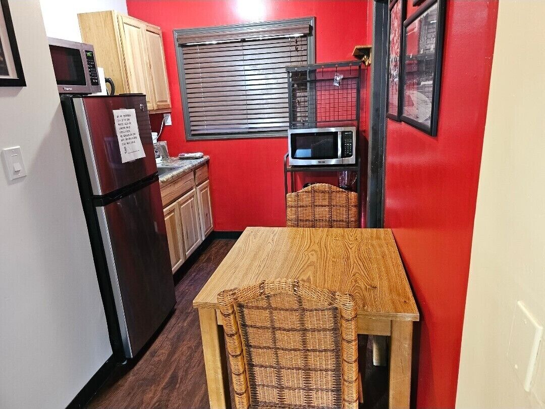 Una cocina compacta con refrigerador, microondas y una mesa de madera.