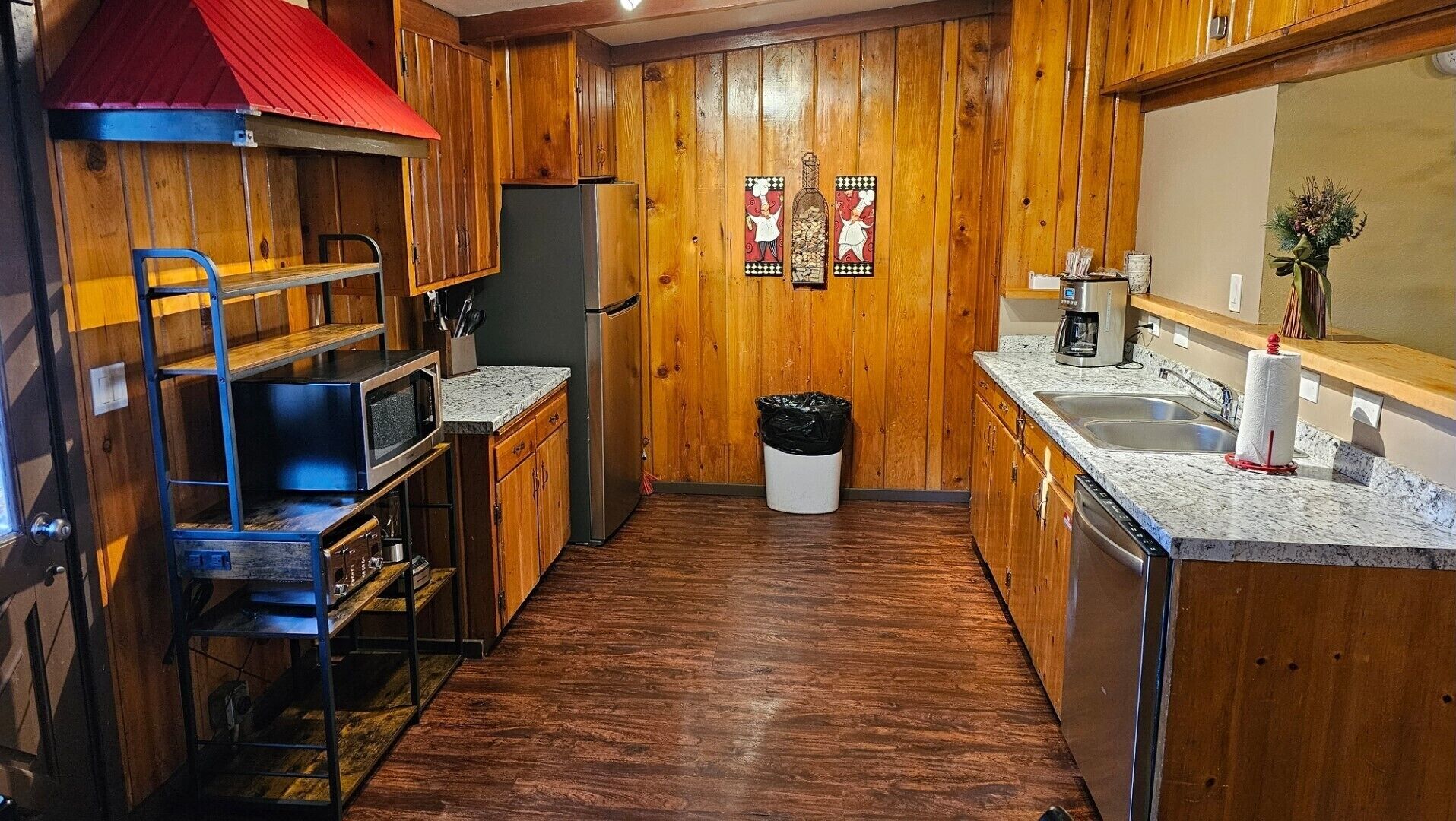 A compact kitchen with wooden walls, a microwave, a coffee maker, and a sink.
